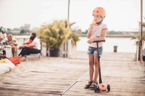 dziewczynka przy hulajnodze Scoot And Ride 3+  w kasku Scoot And Ride 3+