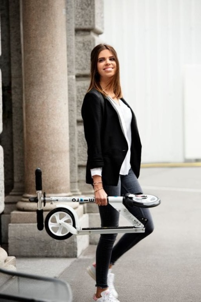 młoda kobieta niesie hulajnogę Micro White Classic
