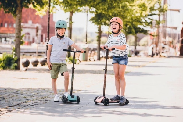 ScootAndRide Highwaykick 5 LED Hulajnoga trójkołowa balansowa ze świecącymi kółkami 5 Plus Forest chłopiec i dziewczyna jadący na hulajnodze