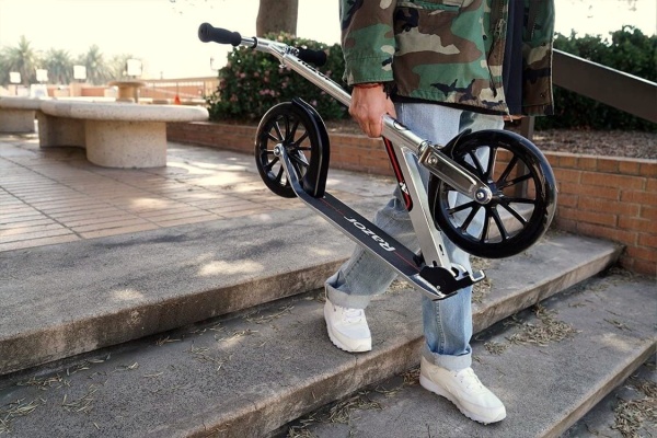 mężczyzna niesie hulajnogę z dużymi kołami 25cm Razor A6 Silver